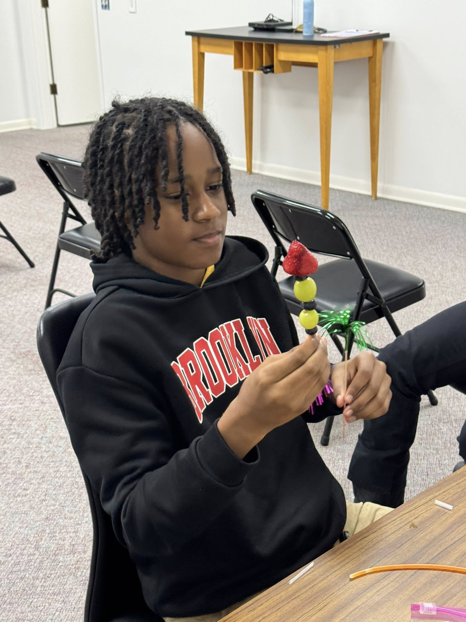 A kid making a fruit kabob.
